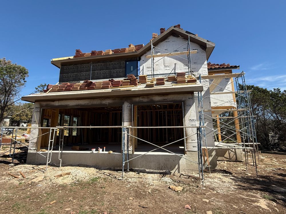 Partially built two-story house with scaffolding under a clear blue sky