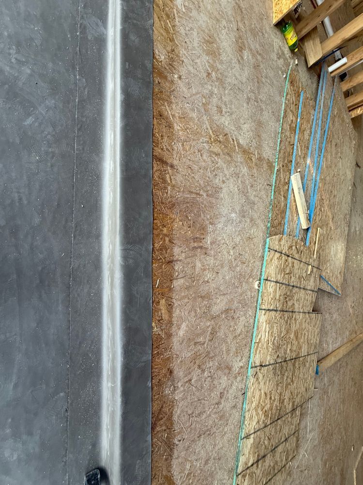 Construction site with a concrete slab, exposed dirt, and wooden framing with blue support stakes.