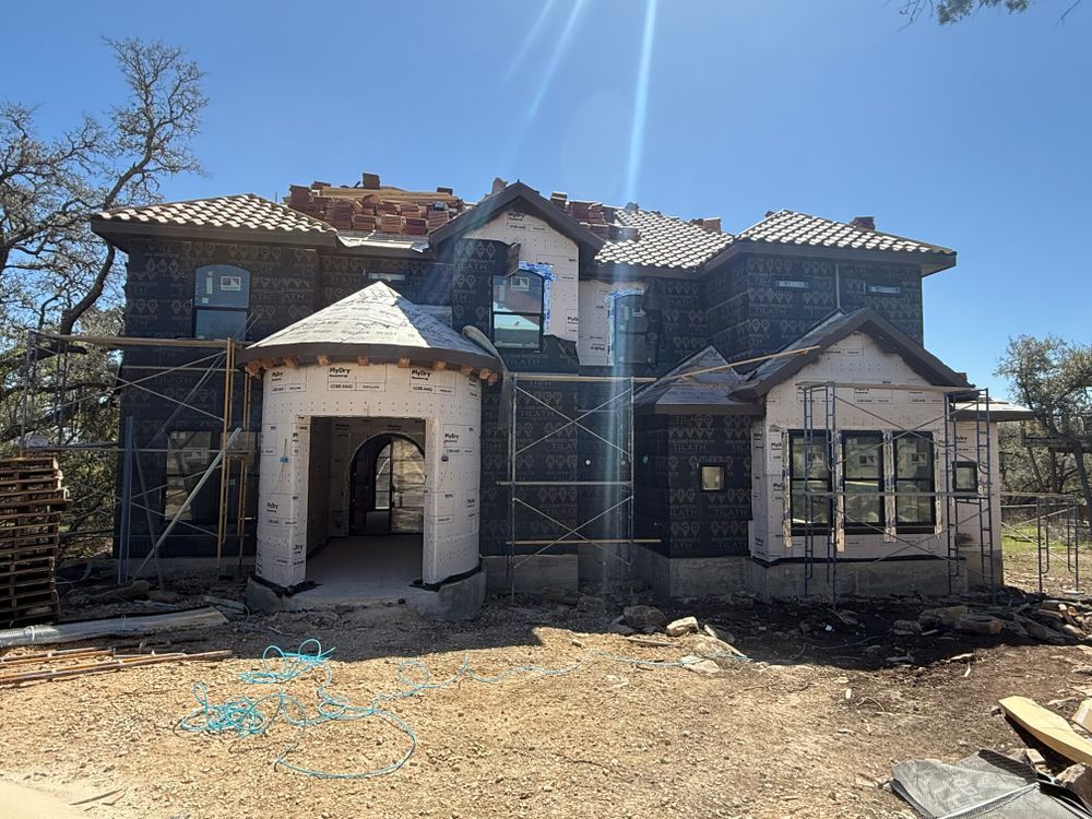 Old house under renovation with exposed framing, white awnings, and debris in the yard.