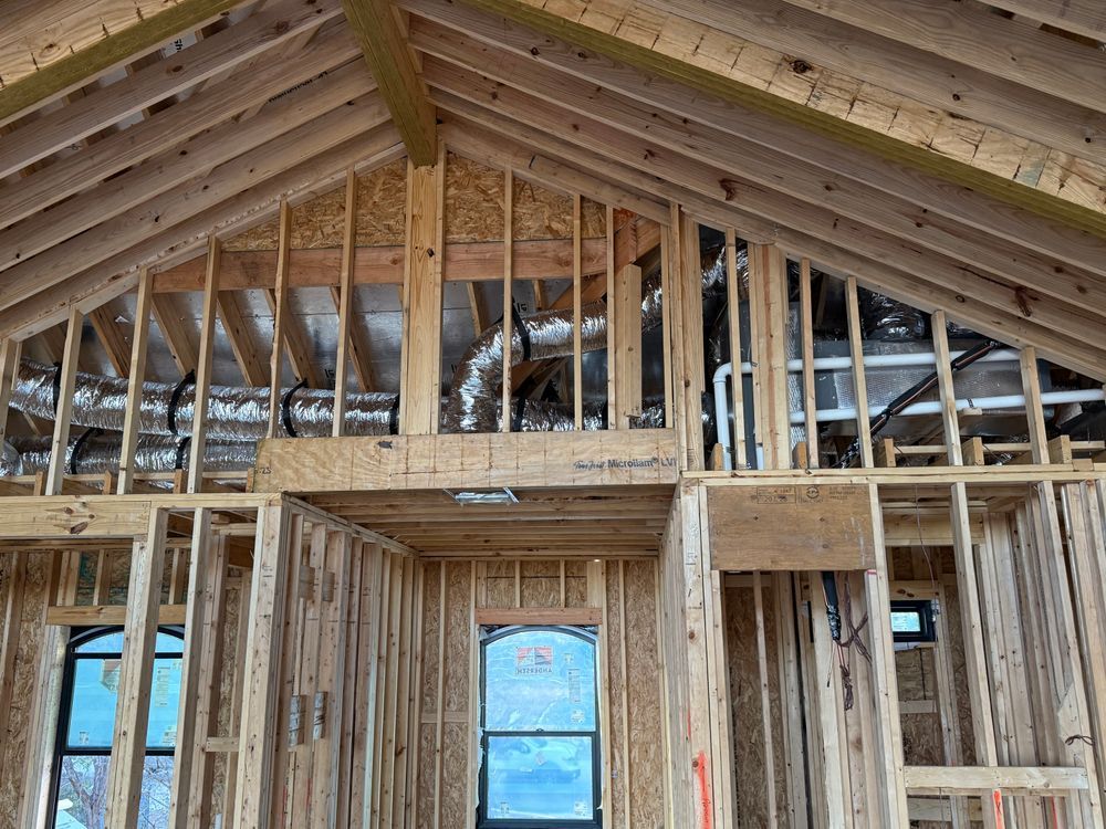 Framed house interior under construction with exposed wooden rafters and wall studs