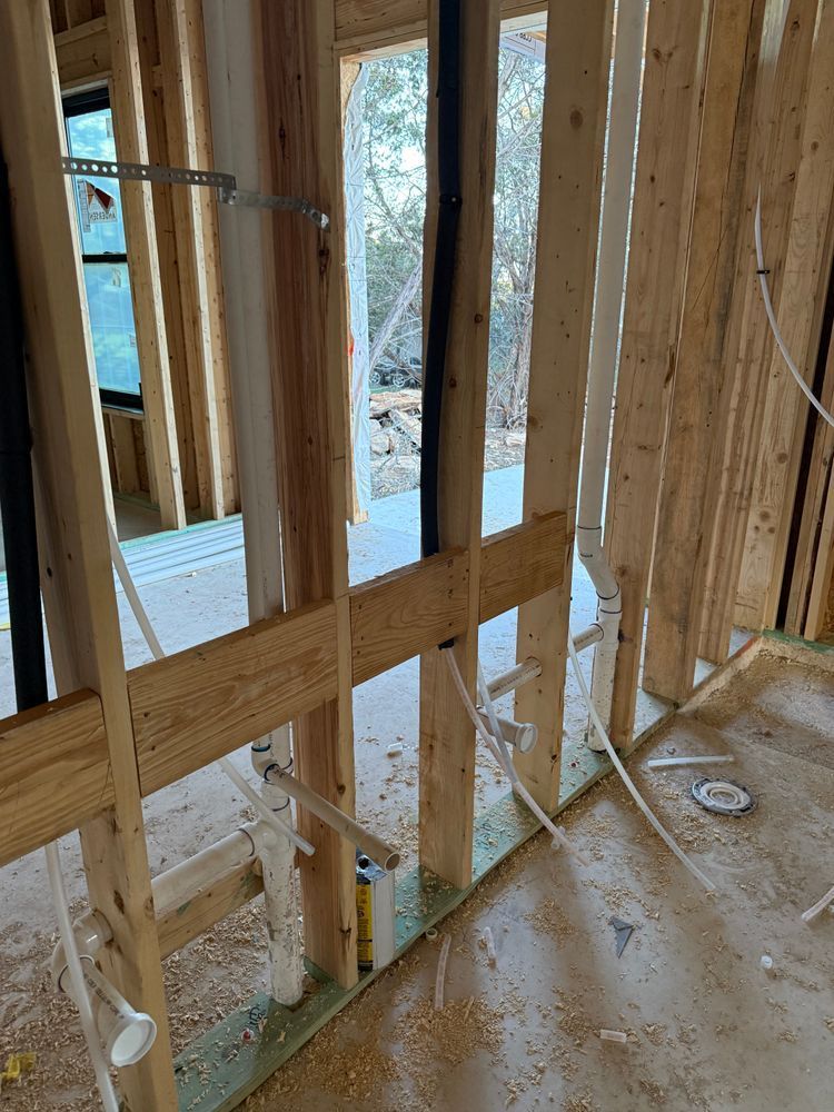 Framed interior wall of a house under construction, with exposed wood studs and wiring.