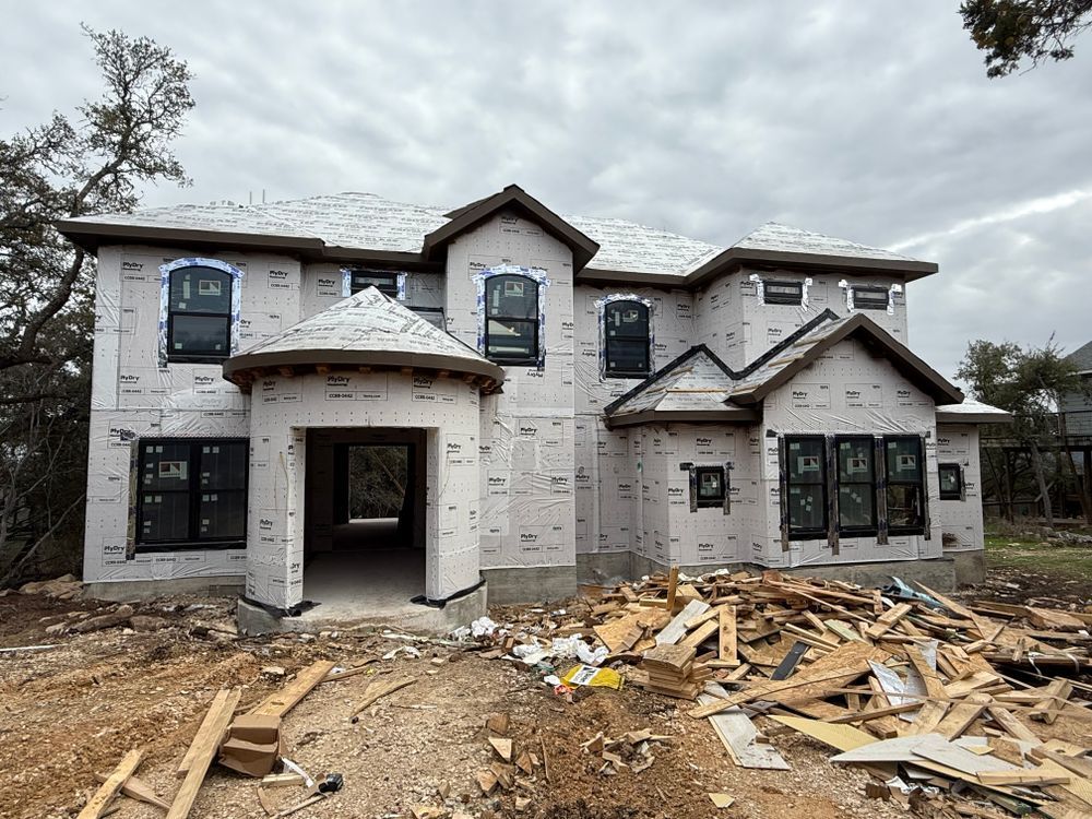Partially built two-story house with white exterior and construction debris in front