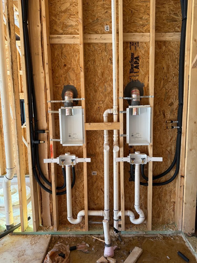 Interior wall framing with two white utility boxes, black cables, and PVC pipes installed between studs