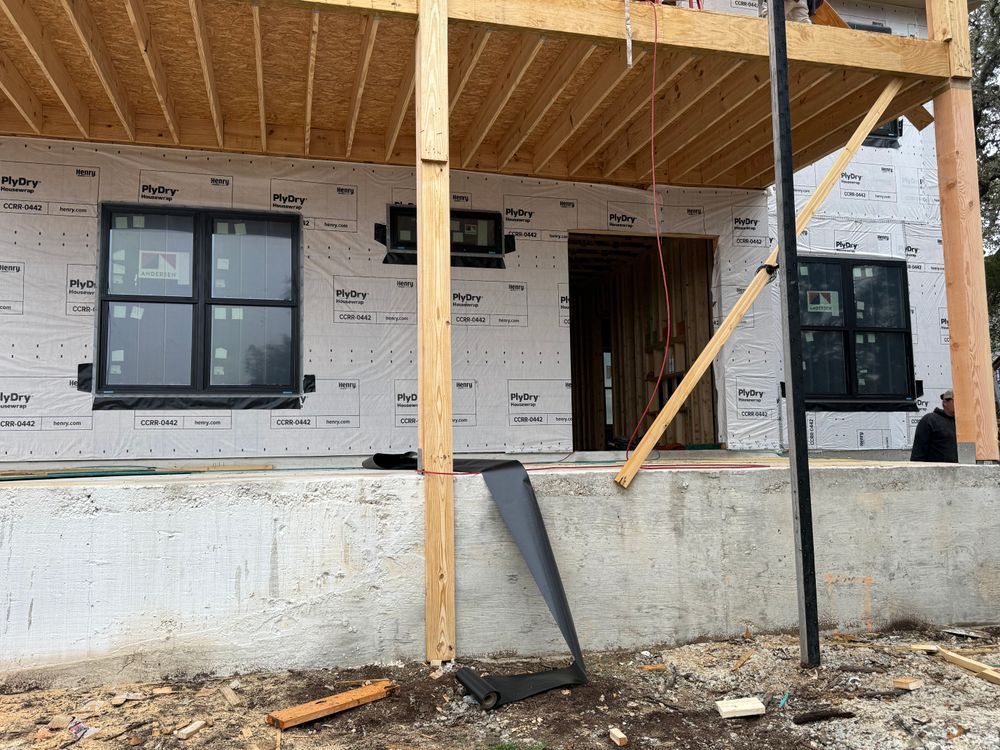 House under construction with wood framing, wrapped exterior, and front porch scaffolding