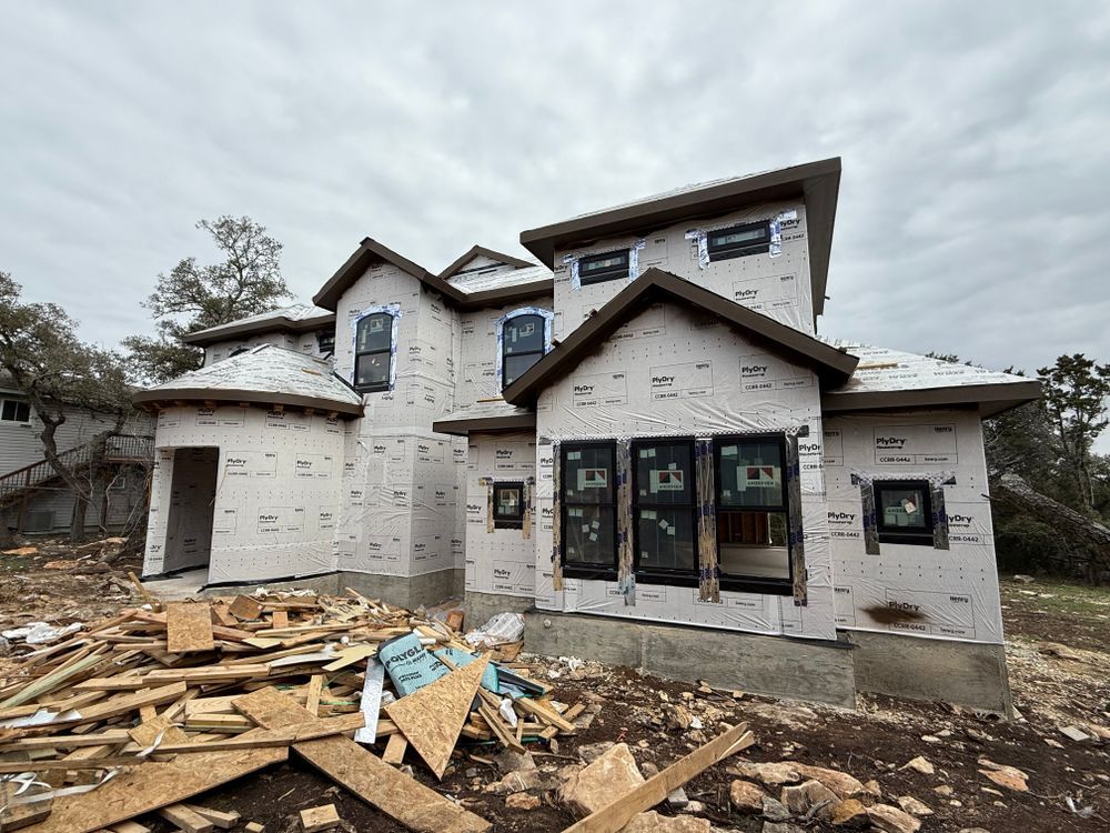 Partially built white house with exposed framing and construction debris in front