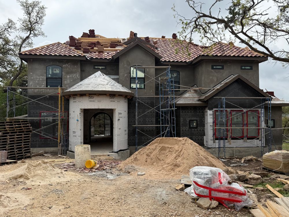 House under construction with scaffolding, exposed roof, and piles of dirt in the front yard