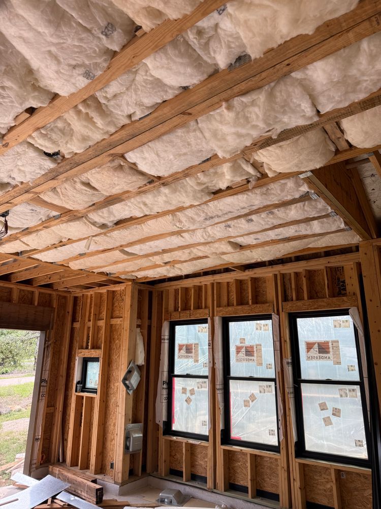 Unfinished room with exposed insulation and framed windows under construction