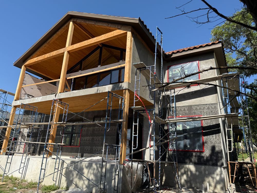 House under construction with scaffolding and exposed wooden roof framing