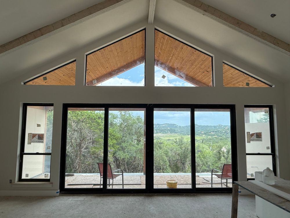 Modern living room with tall glass doors, triangular windows, and a scenic view outside
