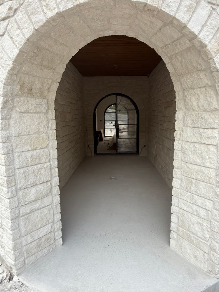 Stone arched hallway with a vaulted ceiling leading to an open doorway beyond