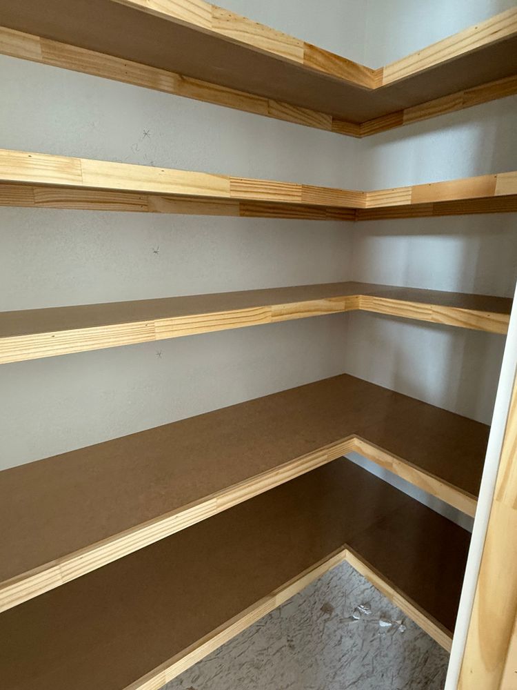 Empty walk-in closet with built-in wooden shelves and brown shelving, viewed from the corner.