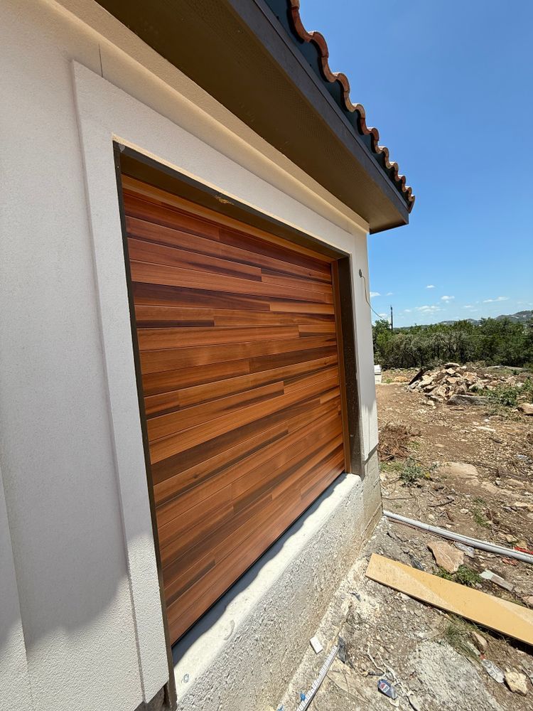 Wood-paneled window shutter on a stucco house exterior beside a rocky construction site