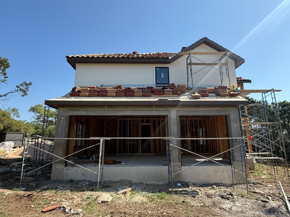 Partially built house with scaffolding and an unfinished front porch under a clear blue sky