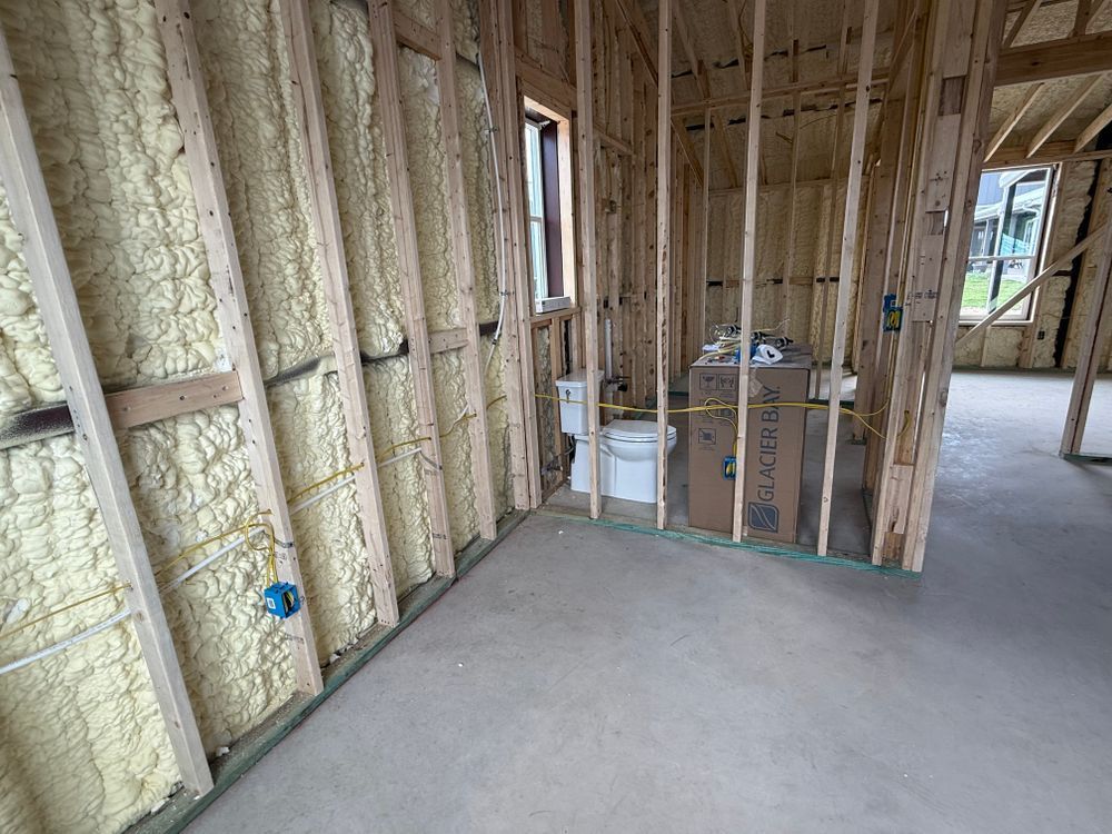Unfinished room with exposed wood framing, spray foam insulation, and a concrete floor