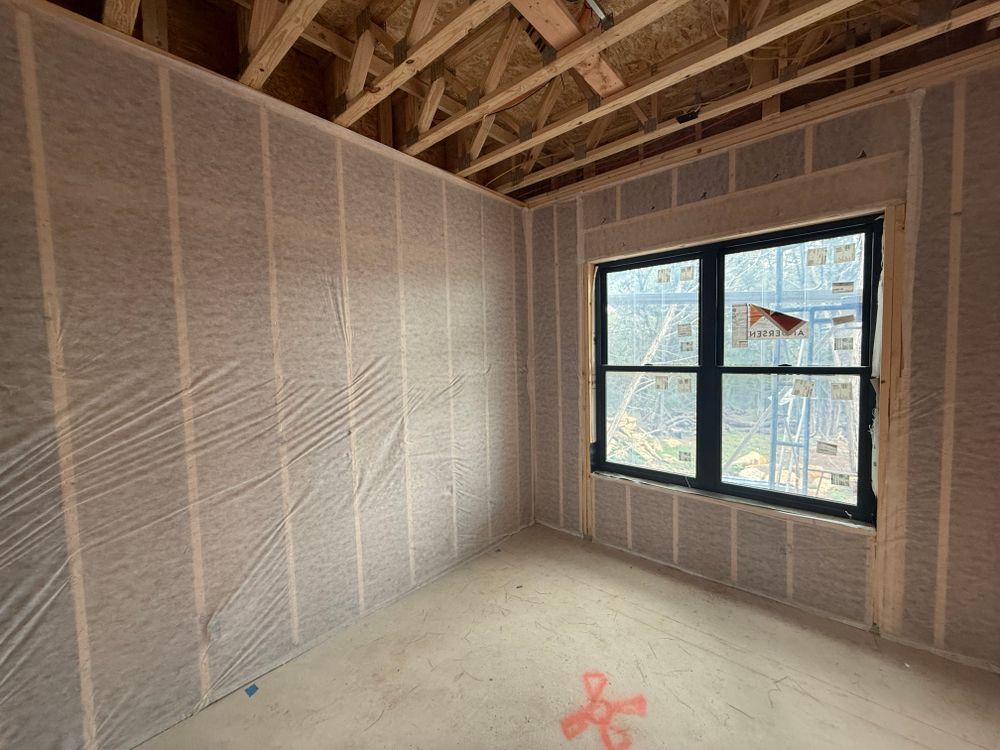 Unfinished room with exposed insulation, sloped ceiling, and a window letting in daylight