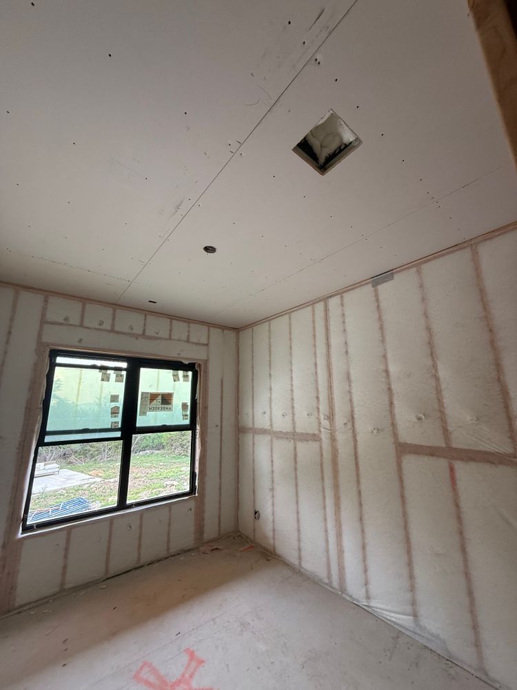 Empty unfinished room with insulated walls, a small window, and a ceiling vent.