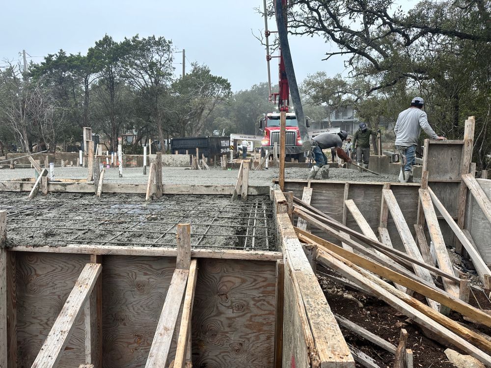 Construction site with concrete forms, wooden supports, and workers pouring concrete outdoors