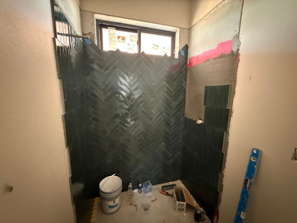 Small bathroom under renovation with black waterproof wall panels, a toilet, and construction materials on the floor