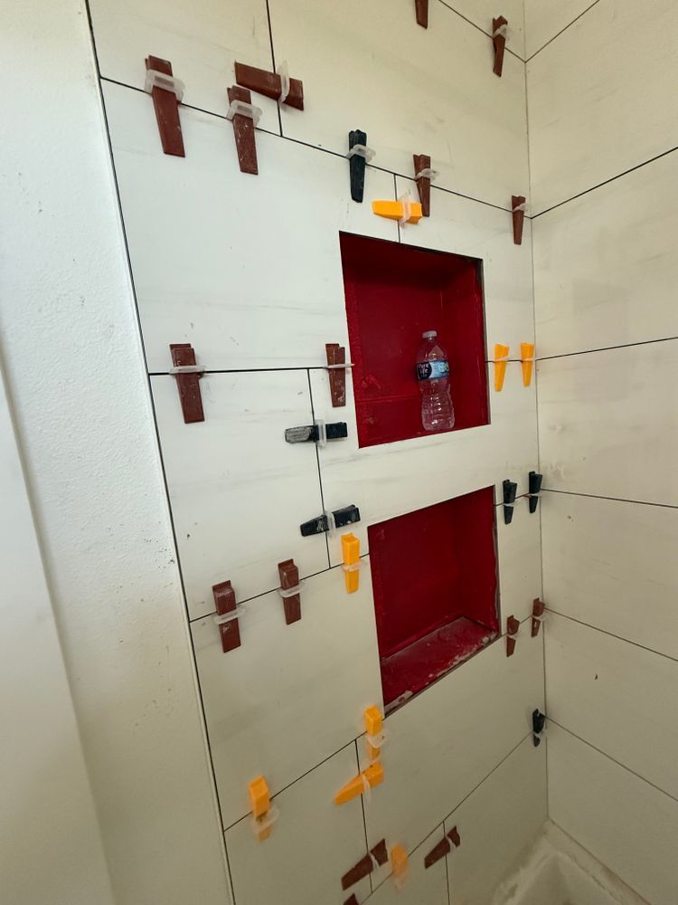 White tiled wall with two red recessed openings and visible metal brackets/clips.