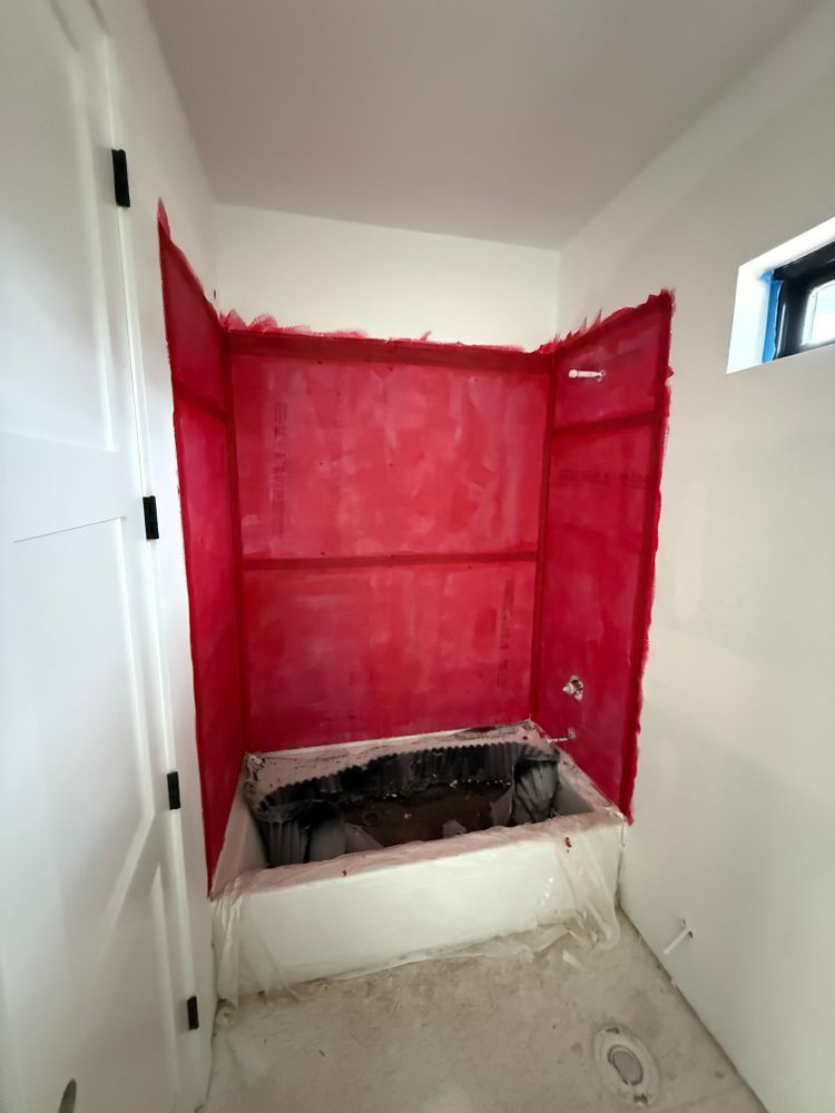 Red-painted bathroom alcove with an unfinished floor opening and a small window on the right.