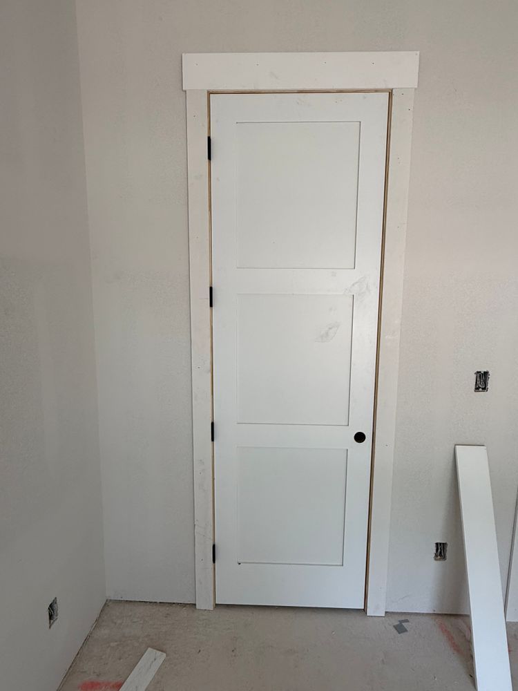 White interior door in an unfinished room with bare walls and floor.