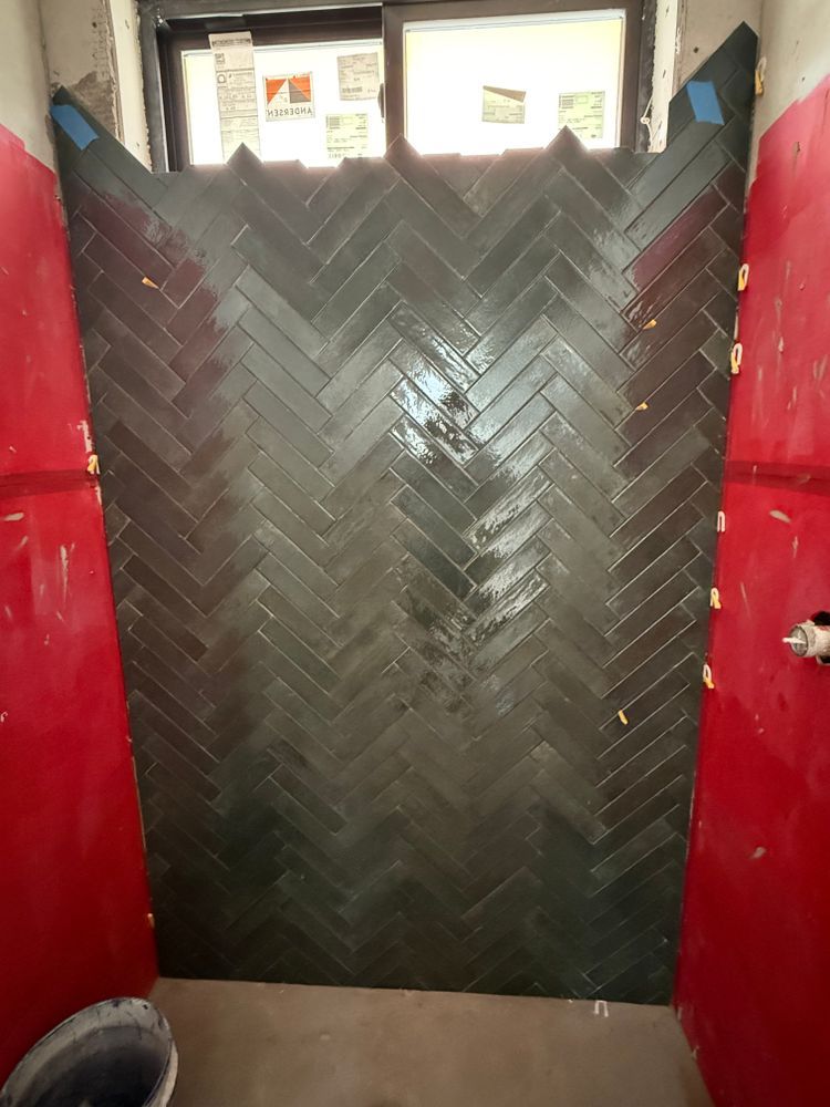 Black chevron-patterned door or wall panel between red walls, with small windows above.