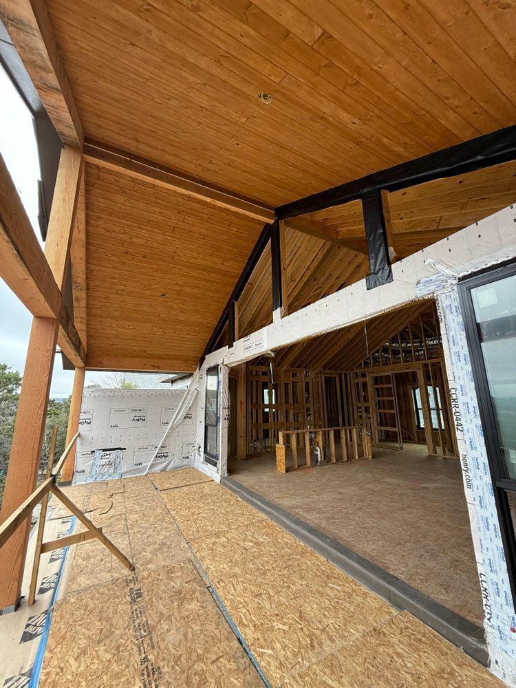 Wood-framed building under construction with plywood ceiling, exposed framing, and open doorway.