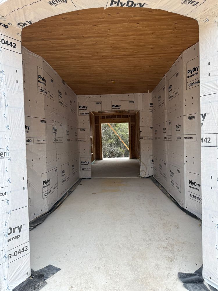 Narrow unfinished hallway with drywall walls, a wood ceiling, and a concrete floor leading to an open doorway.