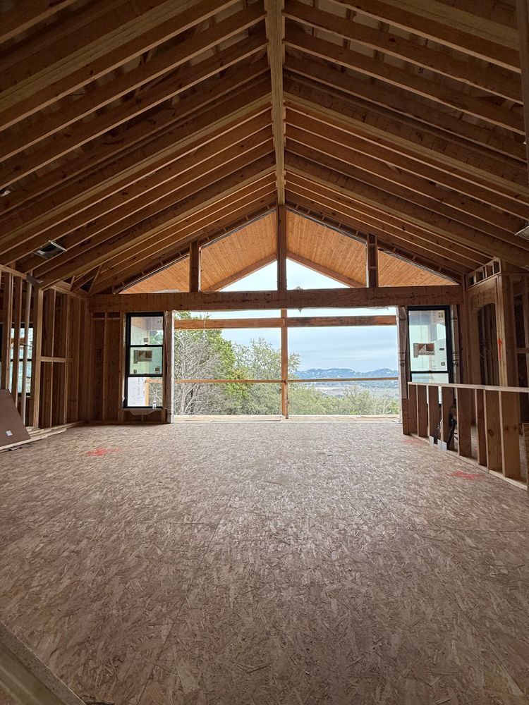 Empty unfinished wooden cabin interior with vaulted ceiling and large windows overlooking water and trees