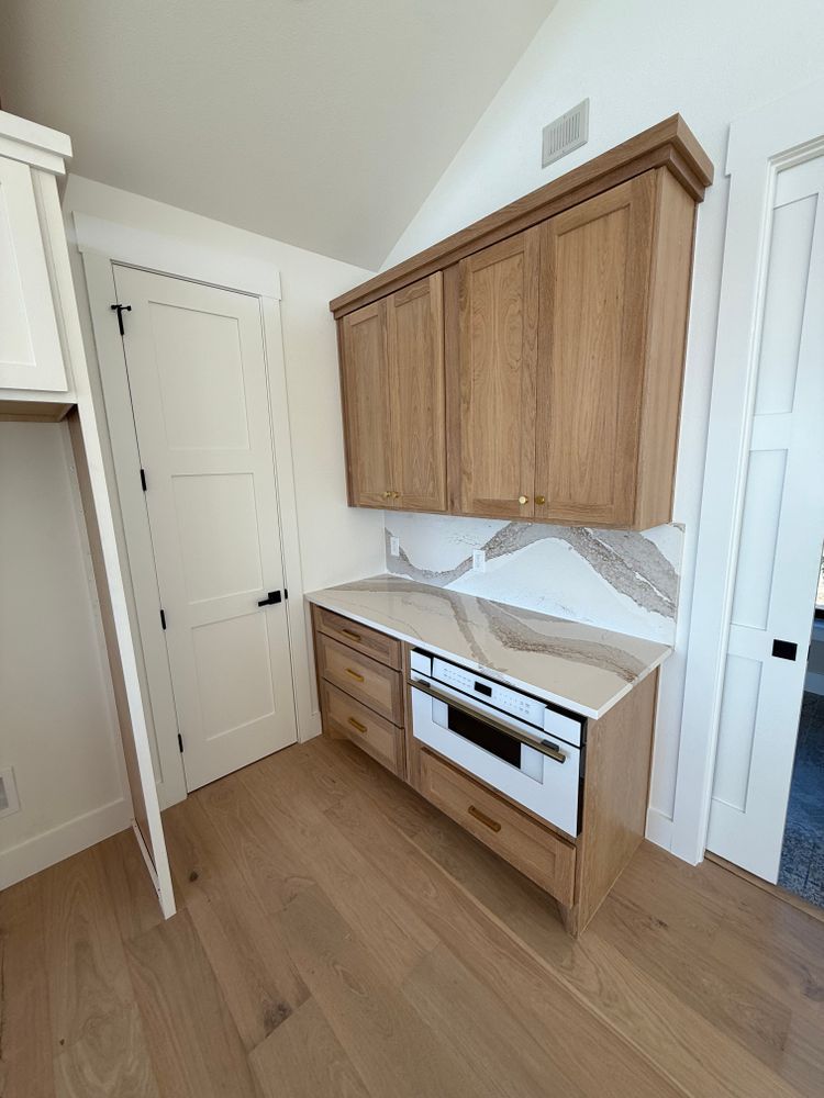 Small kitchen with wood cabinets, white countertop, tile backsplash, and unfinished built-in drawers.