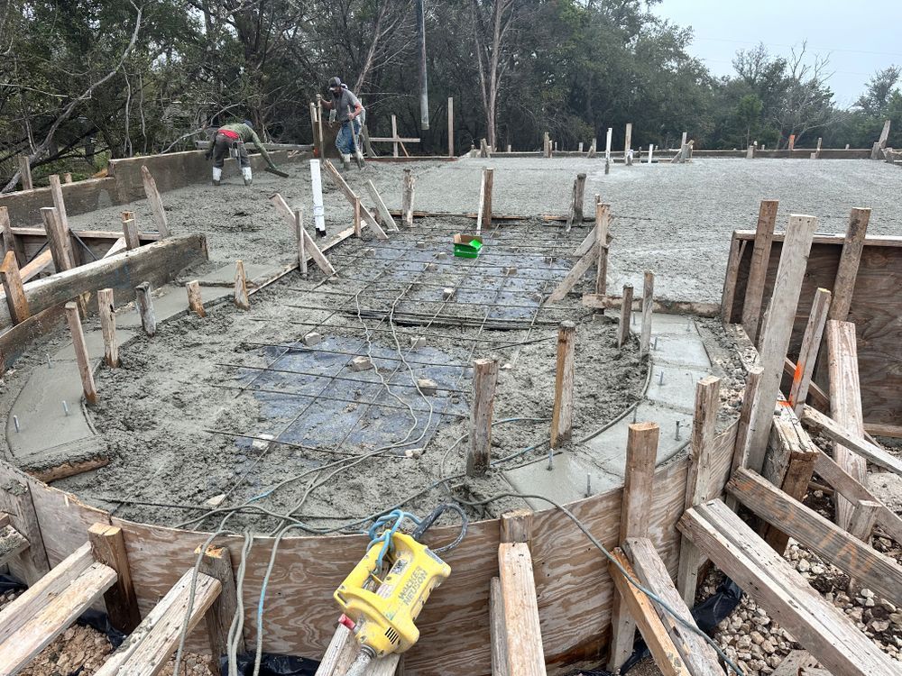 Circular concrete foundation with wooden formwork and workers on a construction site