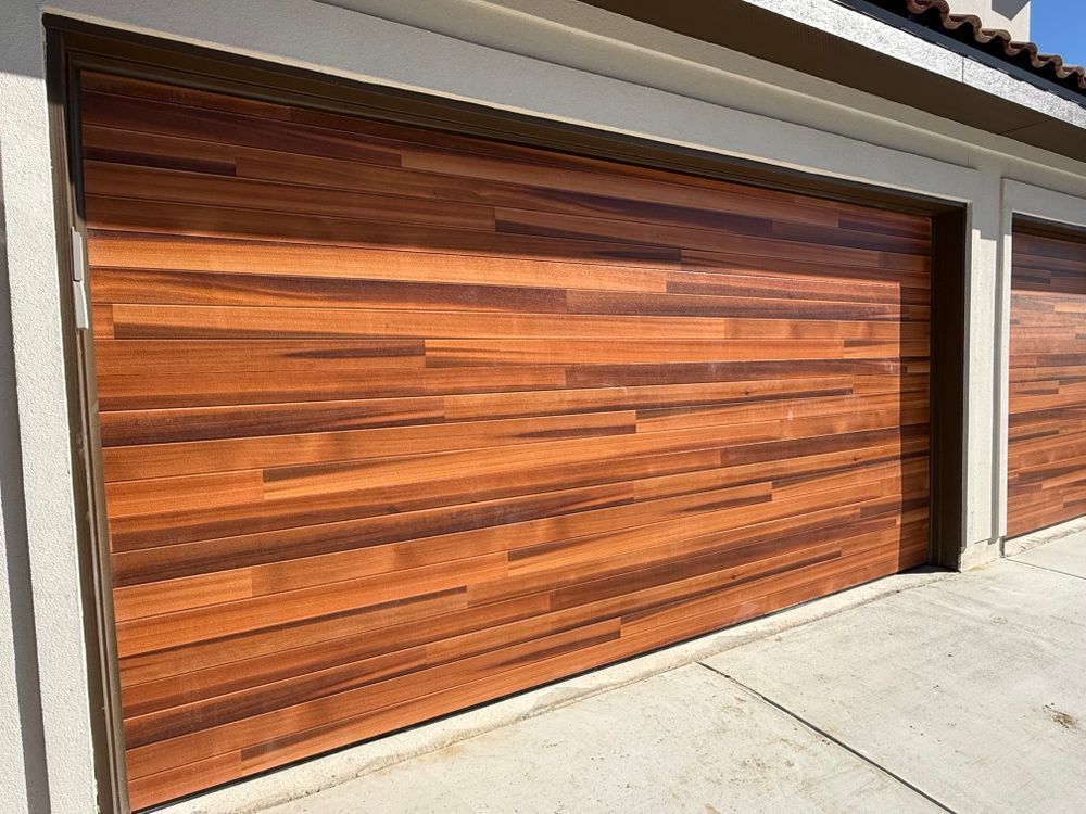 Modern wooden garage doors beside a concrete driveway on a residential home