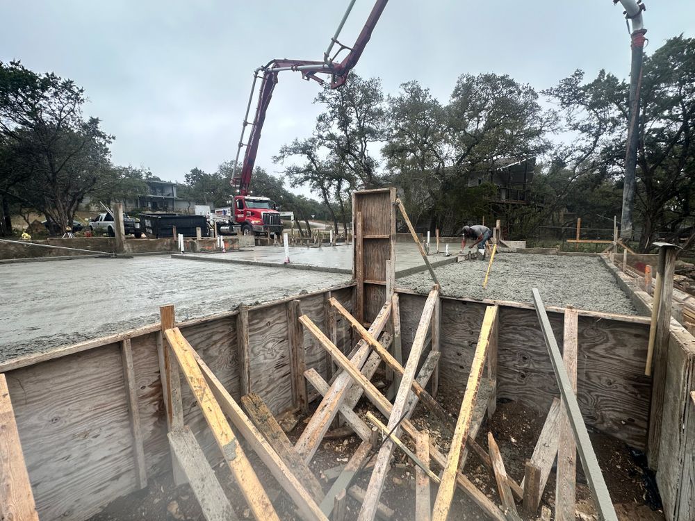 Concrete foundation with wooden bracing and a pump truck pouring concrete at a construction site