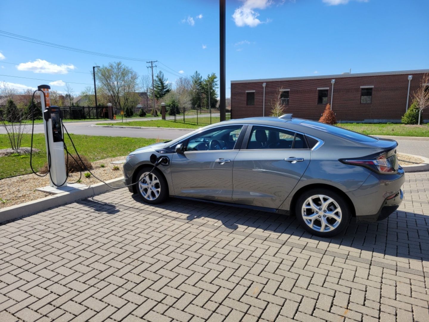 A gray electric car is being charged at a charging station.
