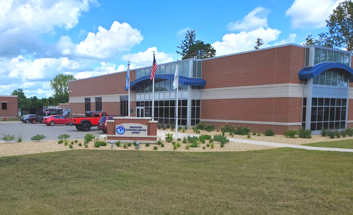 A red truck is parked in front of a large building