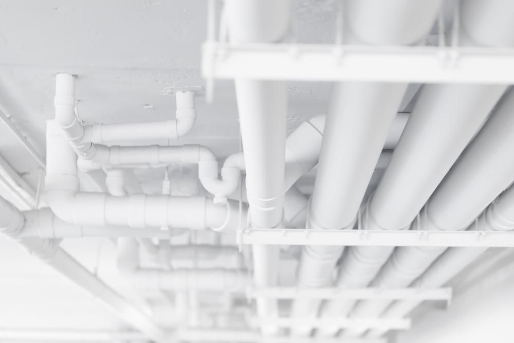 A Bunch of White Pipes Are Hanging From the Ceiling of a Building — Affordable Plumbing In Port Macquarie, NSW