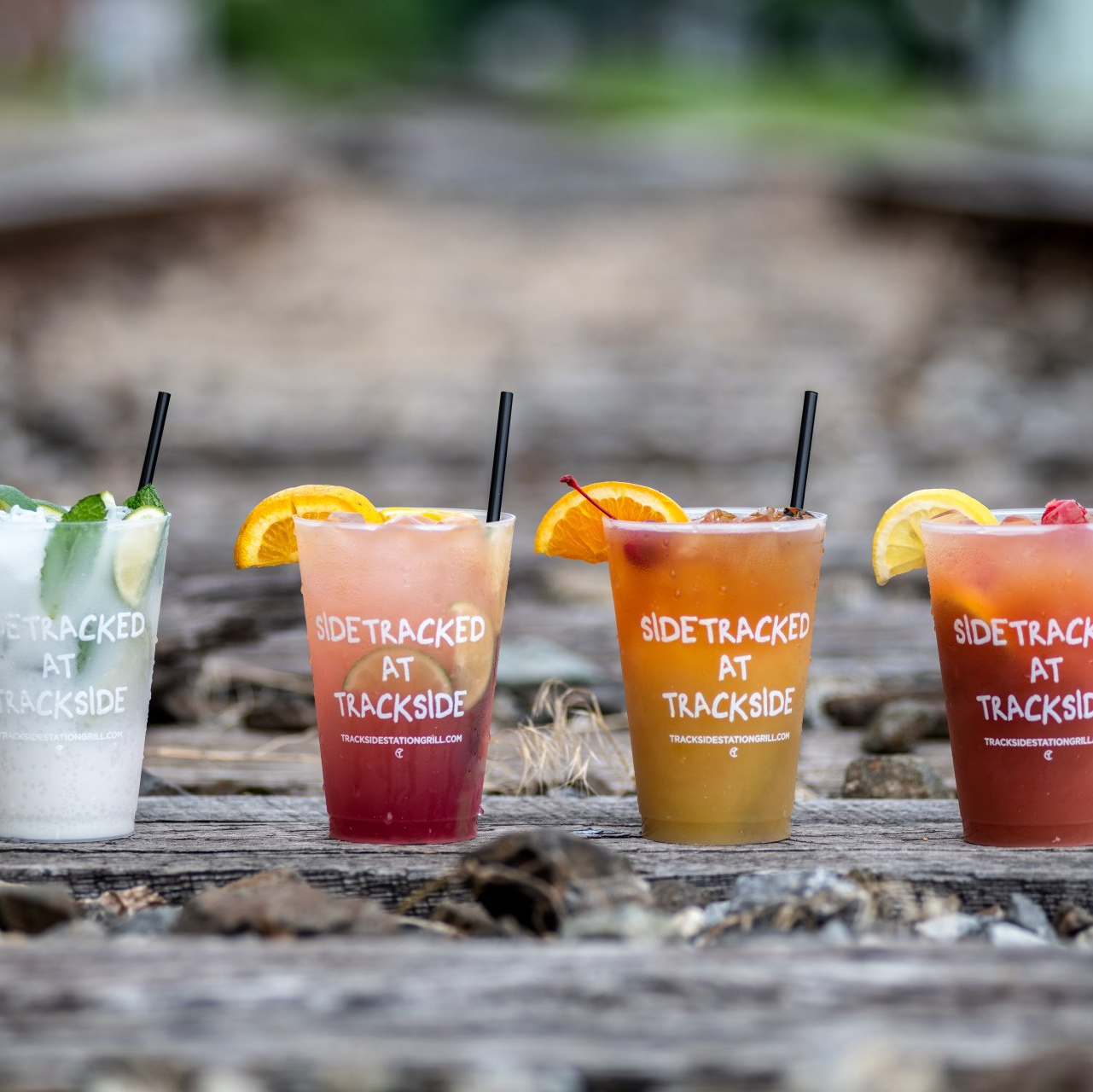 Three cups of side tracked at trackside drinks on a wooden table
