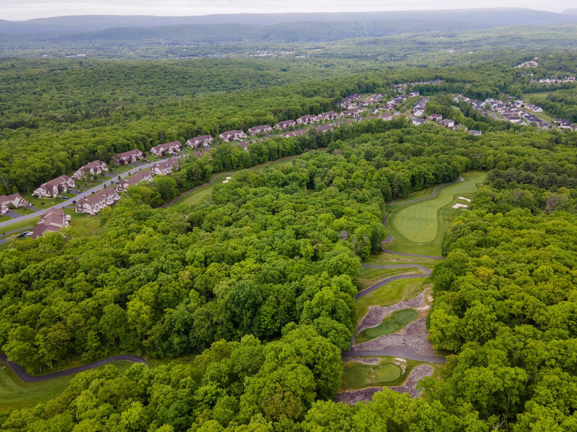 An aerial view of a golf course surrounded by lush green trees.