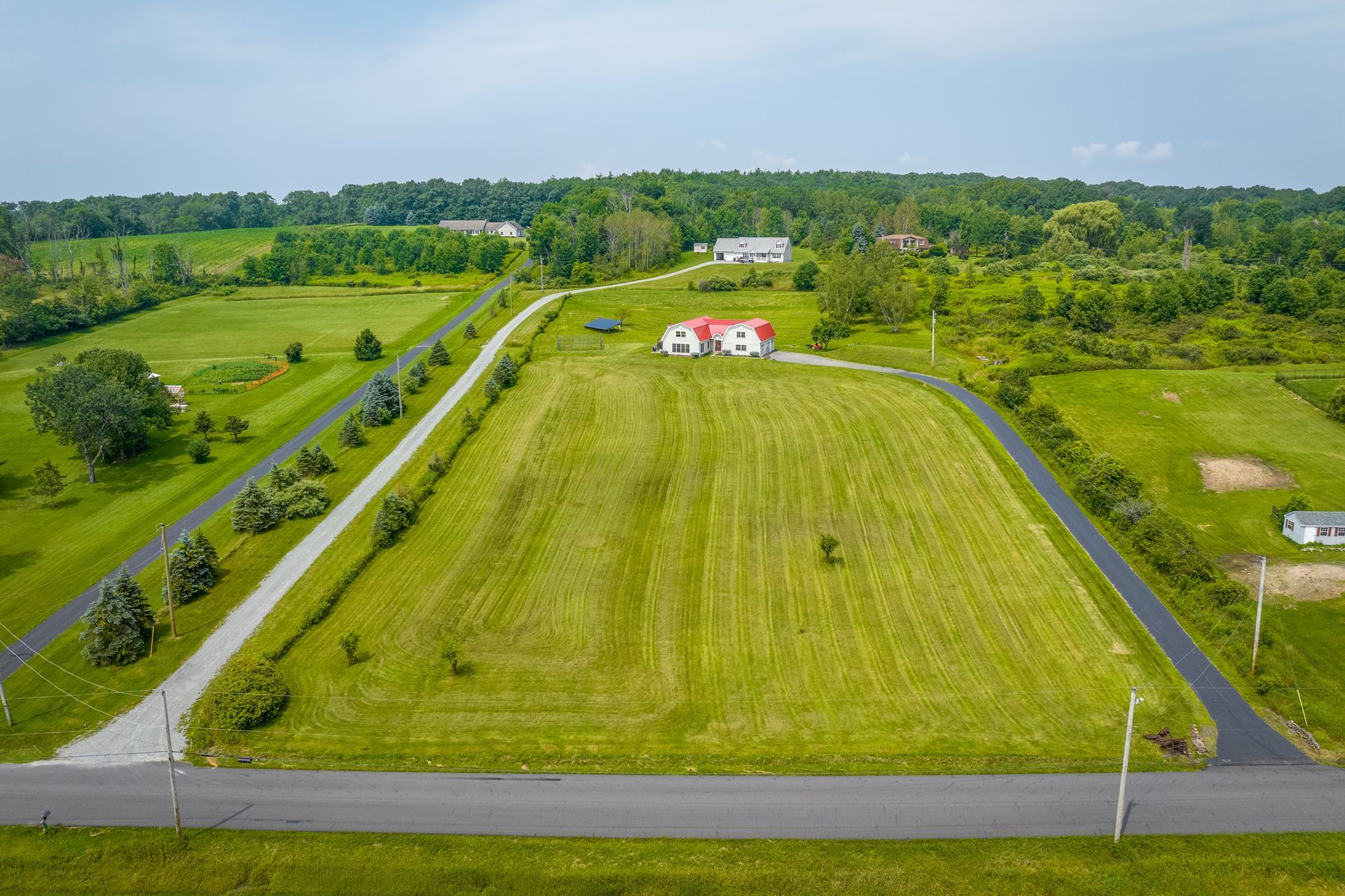 An aerial view of a lush green field with a house in the background.