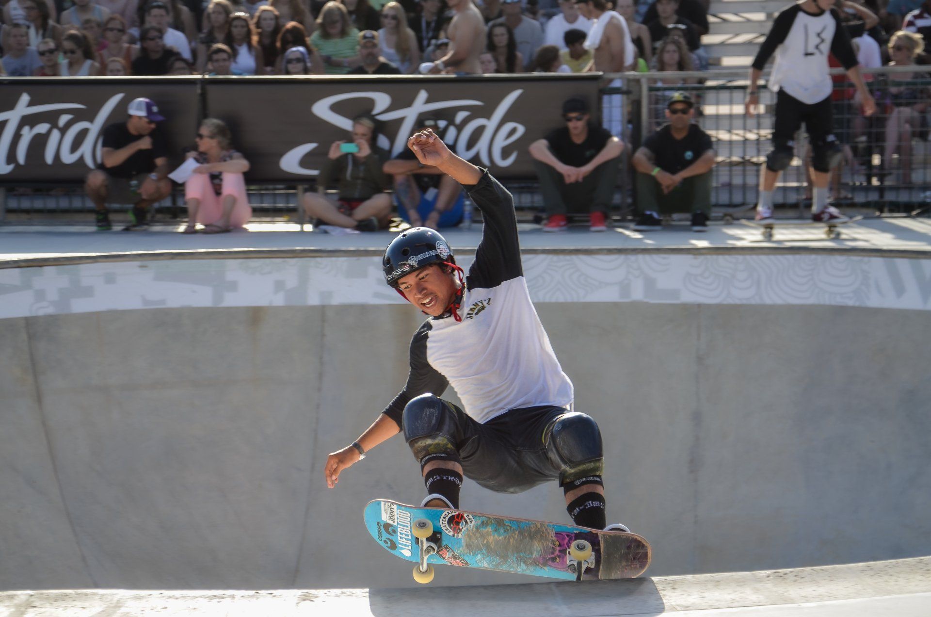 A man is riding a skateboard down a ramp in front of a sign that says stride