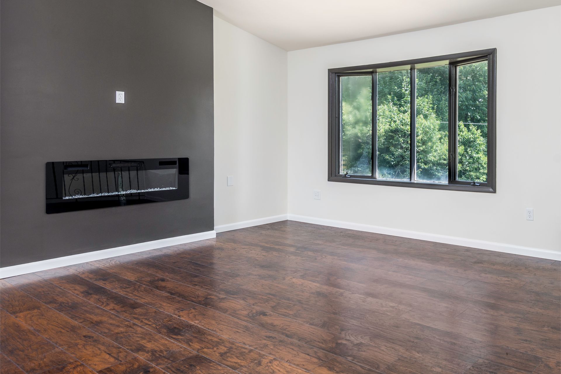 An empty living room with a fireplace and a large window