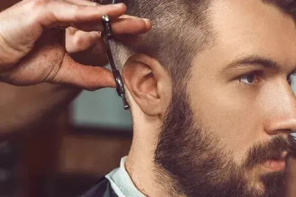 A barber carefully cutting a man’s hair with scissors