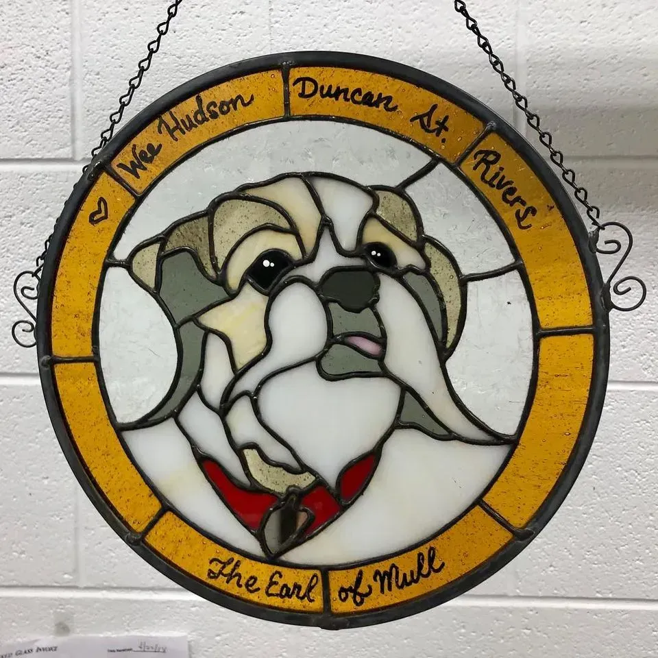 Stained glass bulldog art. Yellow, white, and gray, with text