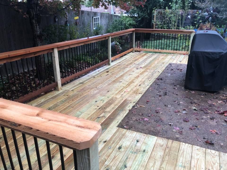 A wooden deck with a grill and a black cover on it.