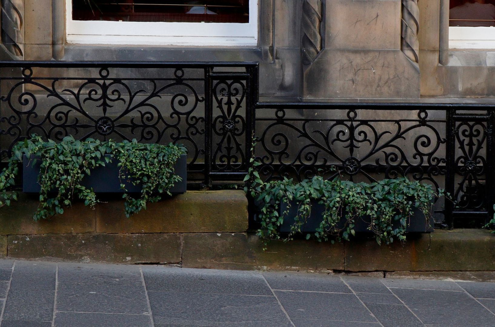 A wrought iron railing with planters in front of a building