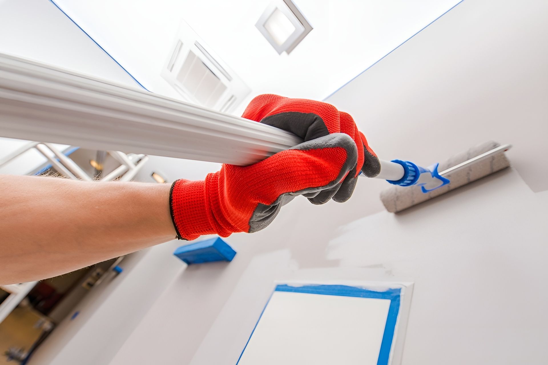 Hand with Red Glove Paints a White Wall with A Roller and Extension Pole — Frenchy’s Plaster & Paint in Palmerston, NT