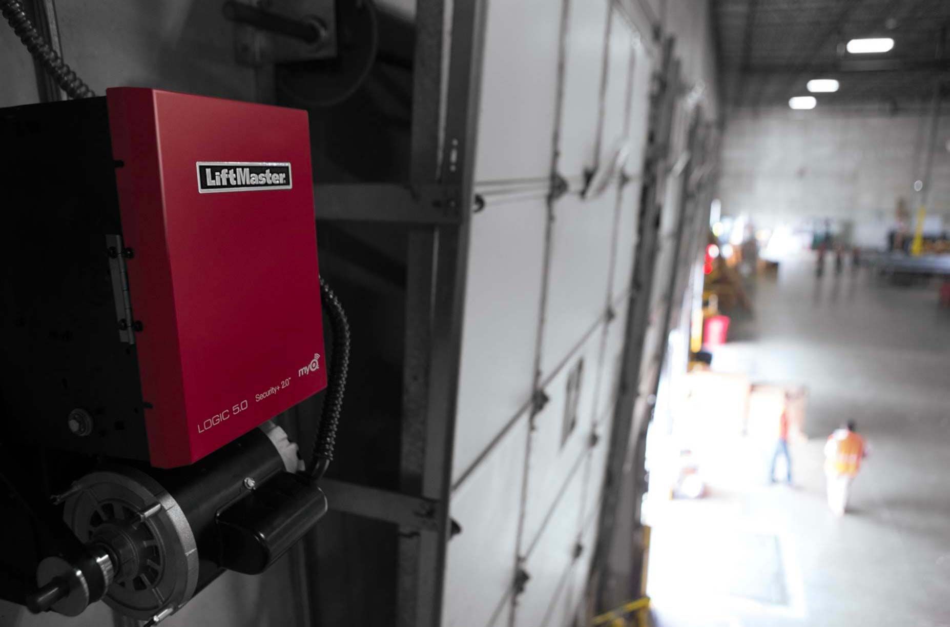 Red motor and control box on warehouse door with open warehouse in background.