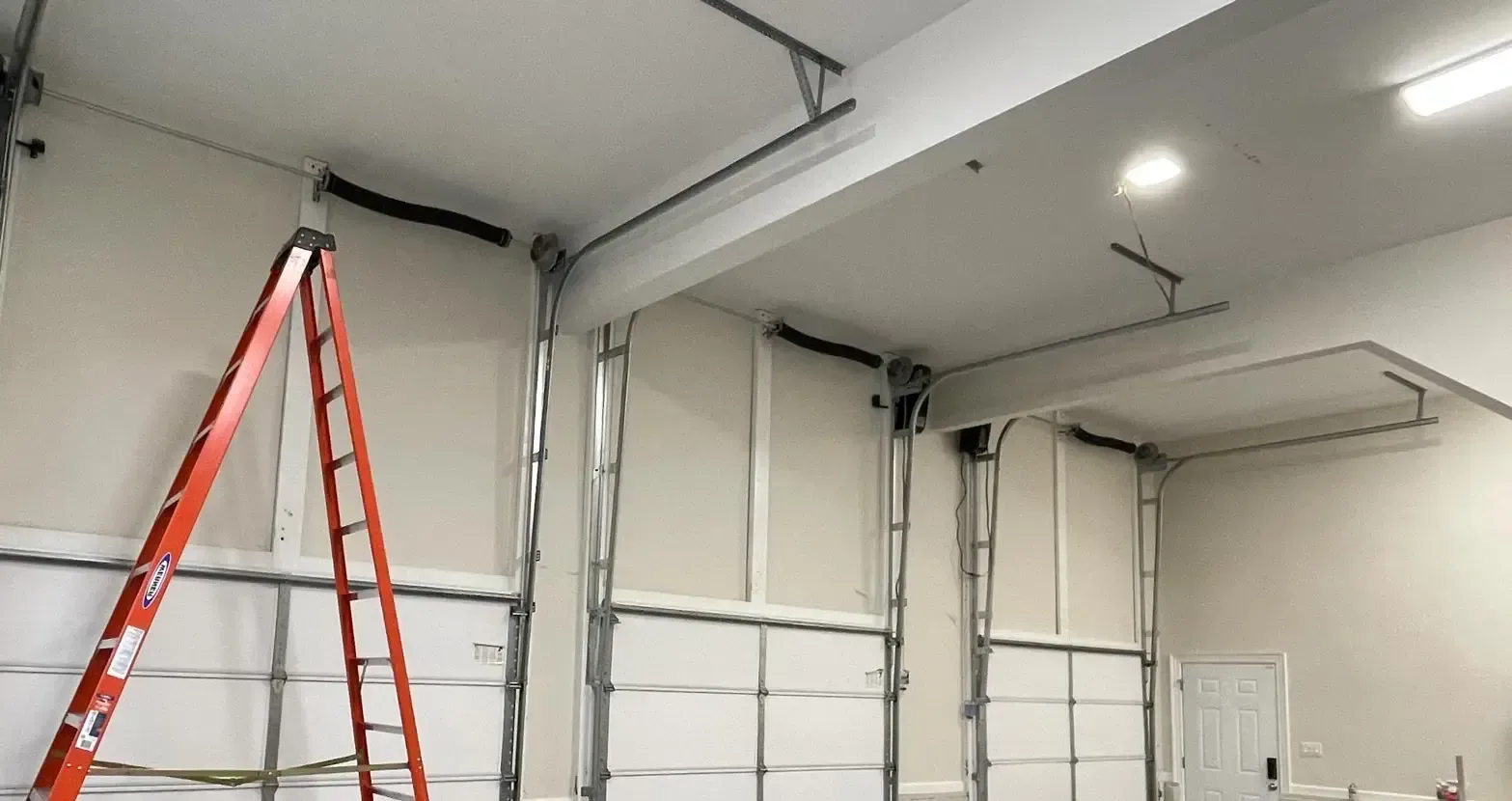 Open garage door, gray panel, revealing garage interior with tools and equipment.