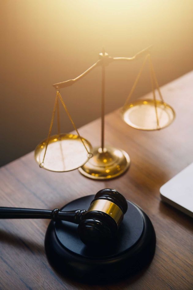 Law books with a scales of justice and judge's gavel on a desk under warm light