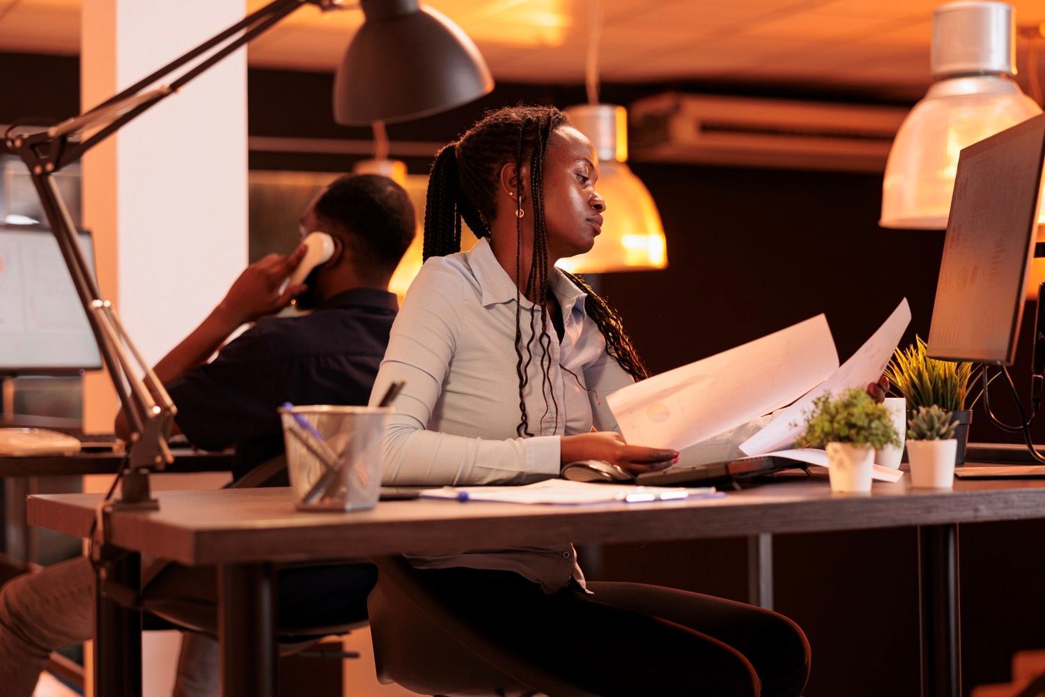 Two coworkers reviewing papers at a desk in a warmly lit office
